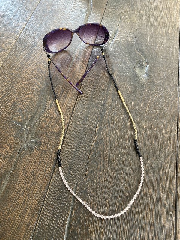 Geflochtenes Makramee-Brillenband mit Perlenabschnitten an Sonnenbrille auf Holz