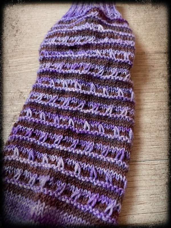 Gestrickte Socke oder Beinstulpe in Lila und Braun mit Lochstreifen