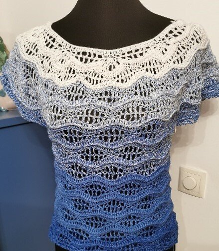 Kurzärmeliges Häkelshirt in Weiß und Blau auf Schaufensterpuppe, deutlich sichtbares Wellen‑Lochmuster