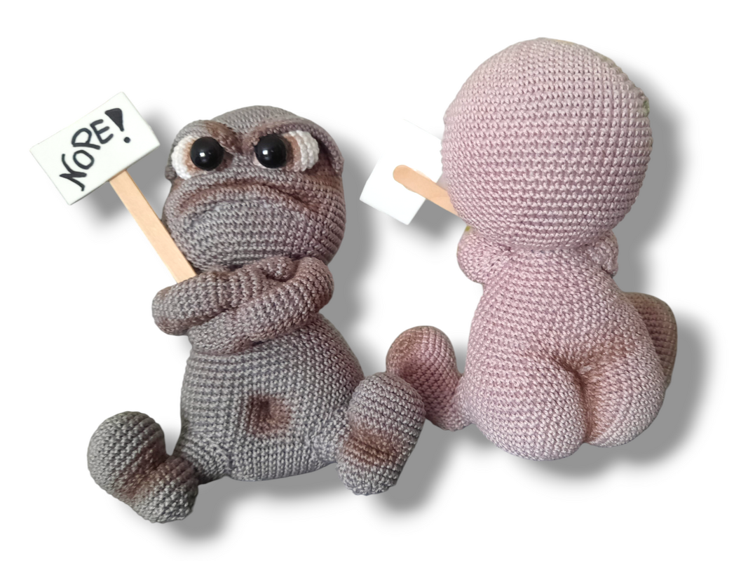 Close front and back study of crocheted amigurumi showing stitch detail, rounded limbs with crossed arms, a small sign on a wooden stick, and a rear view of a companion figure.