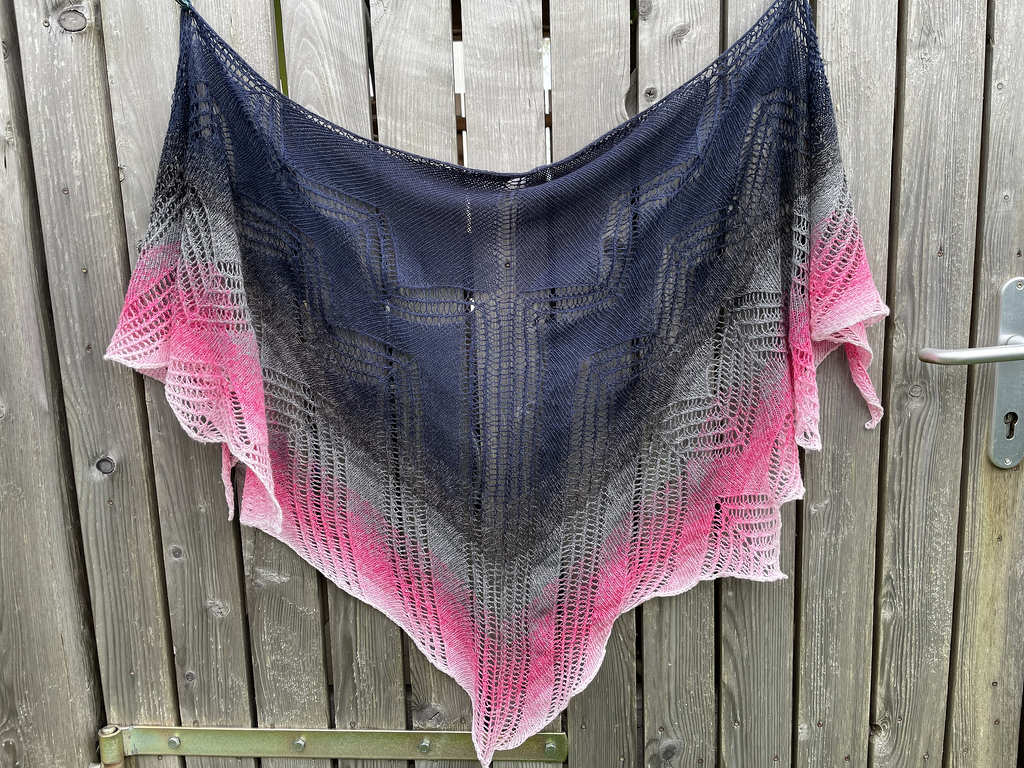 Gestricktes Dreieckstuch mit Farbverlauf in Blau, Grau und Pink an Holzzaun