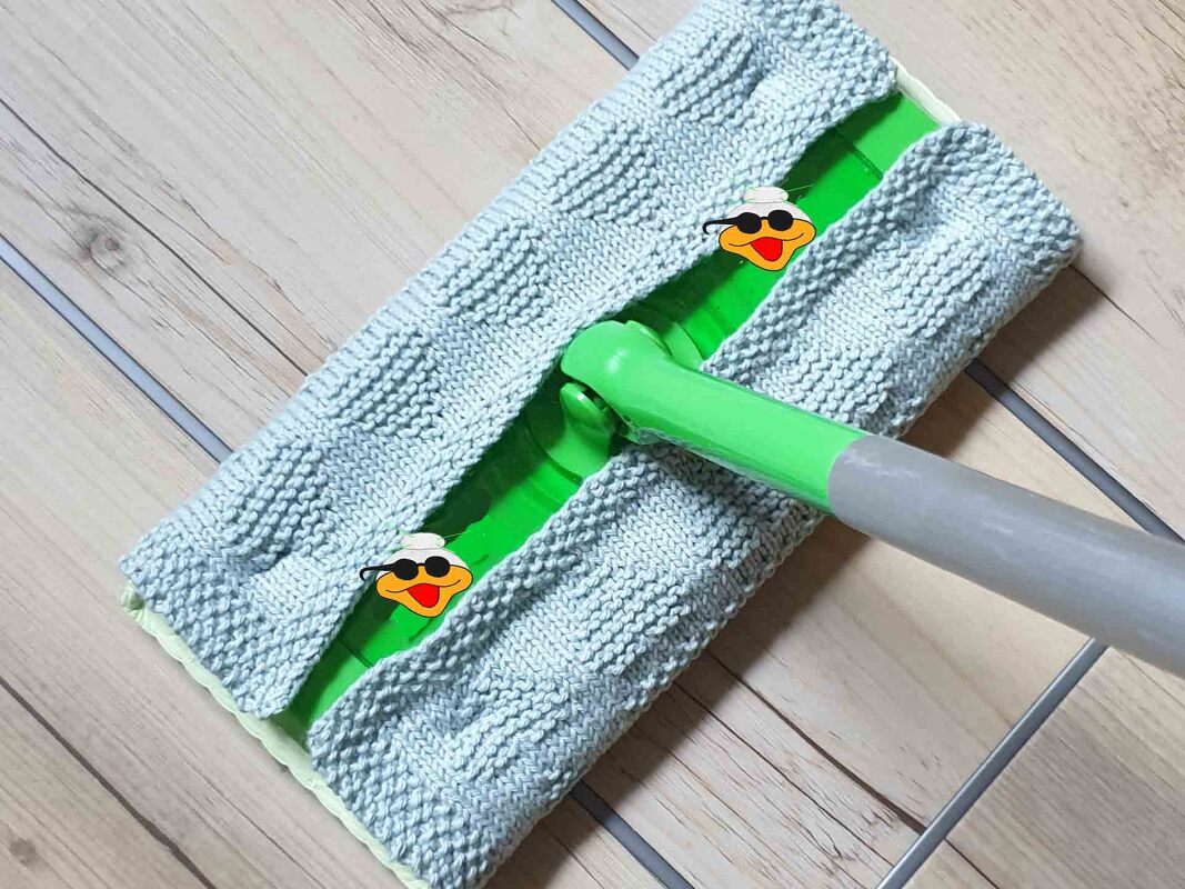 Detailaufnahme gestrickter hellgrauer Moppbezug mit Kästchenmuster auf grünem Moppkopf