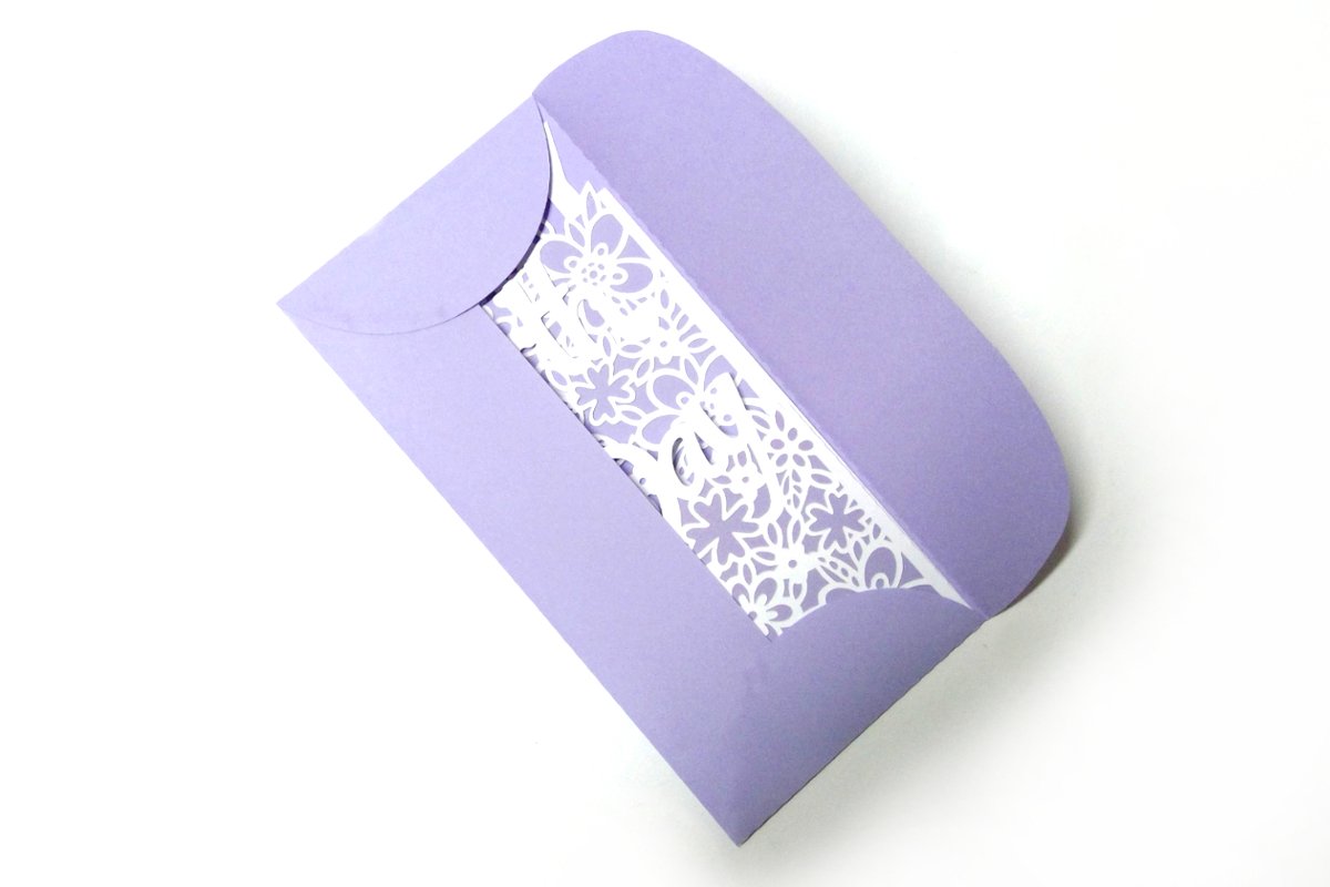 Lila Umschlag mit weißem, durchbrochenem Blumenmotiv.