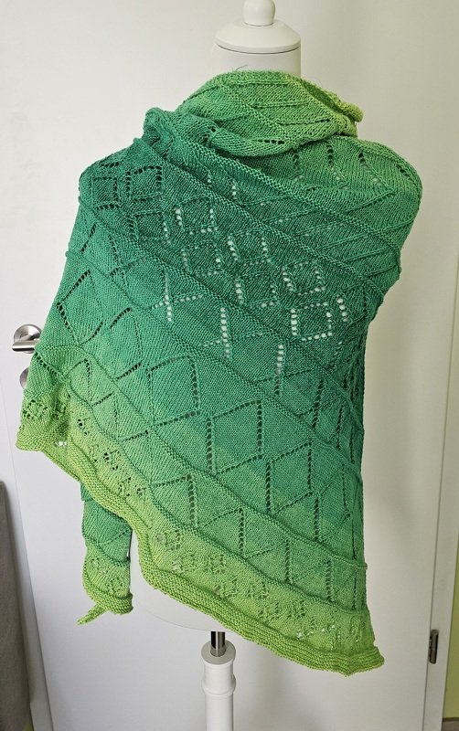 Gestricktes Dreieckstuch in Grüntönen mit diamantförmigem Lochmuster, auf Büste drapiert