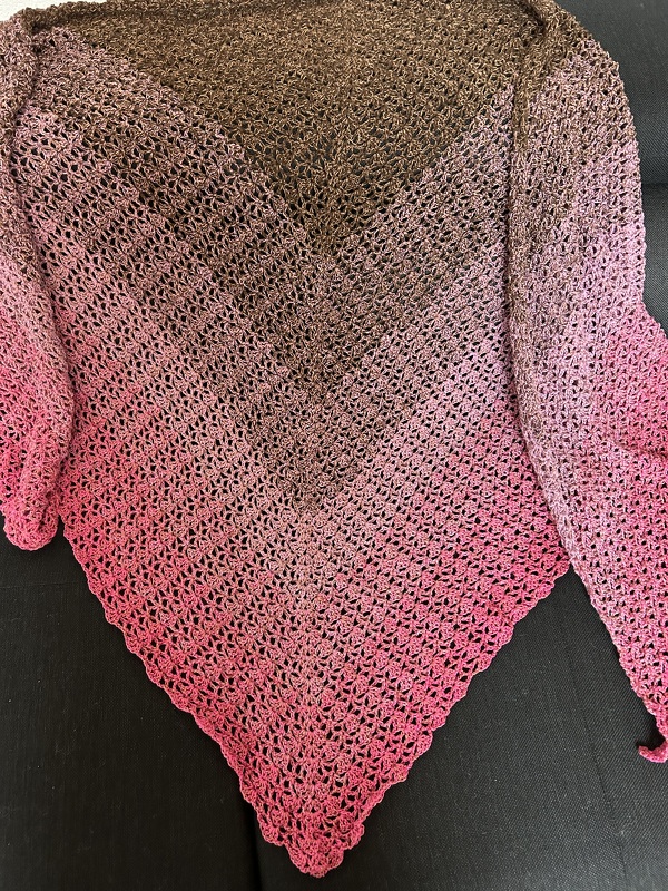 Gehäkeltes Dreieckstuch in Braun und Pink mit Farbverlauf auf dunklem Untergrund
