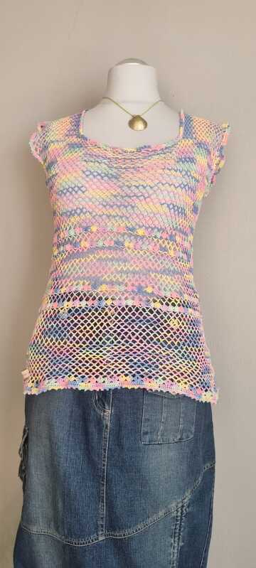 Gehäkeltes pastellfarbenes Netz-Top mit kurzen Ärmeln auf Schaufensterpuppe über Jeansrock