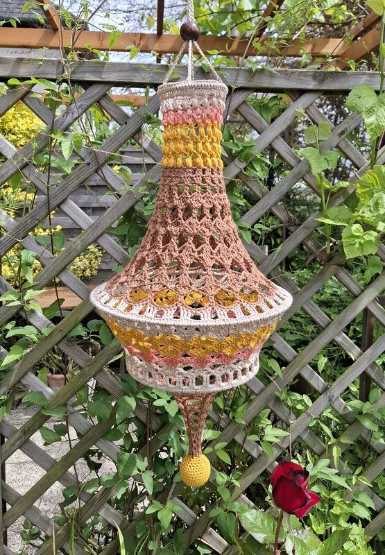 Gehäkelter Lampion in Rosa, Gelb und Beige an Holzspalier