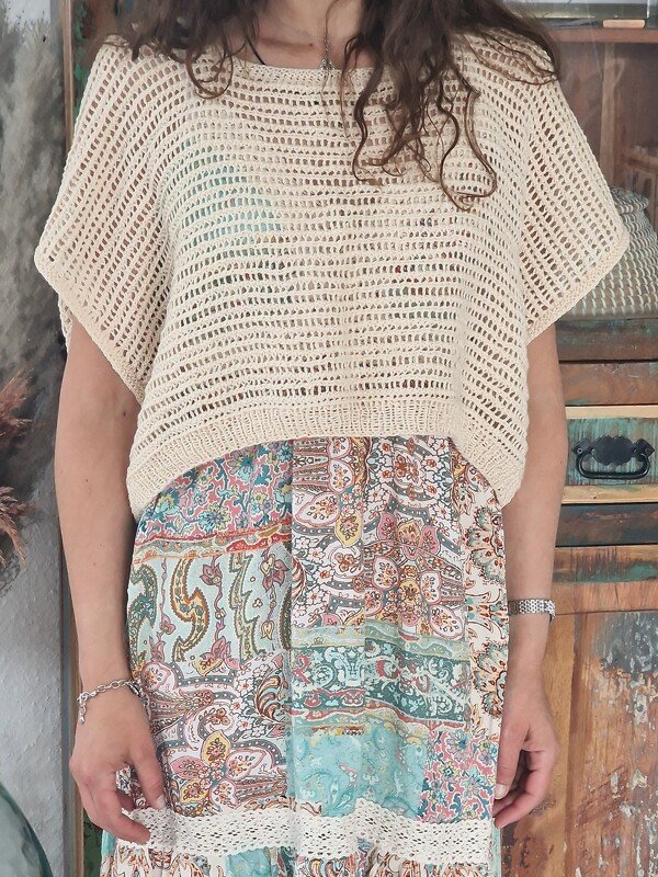Cremefarbenes offenes Stricktop über buntem Patchwork-Rock