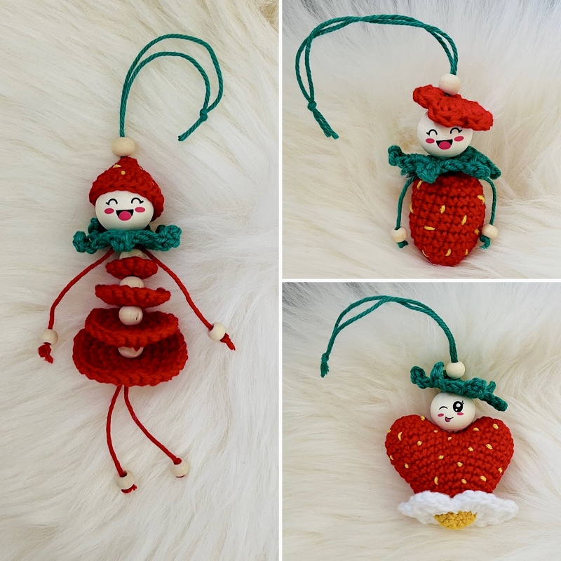 Drei gehäkelte Anhänger: ein Püppchen, eine Erdbeere und ein Herz, mit Holzperlenköpfen auf hellem Hintergrund.
