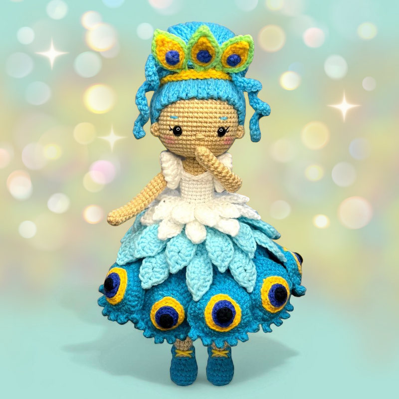 Blue peacock-inspired amigurumi crochet doll wearing a crown and layered petal skirt