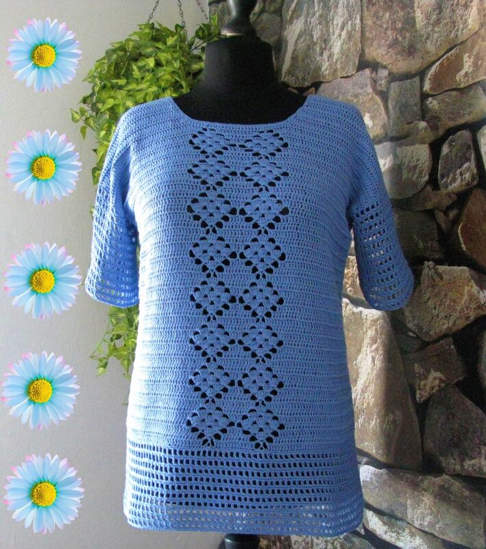 Hellblaues gehäkeltes Damen-Shirt mit kurzen Ärmeln und durchbrochenem Rautenmuster auf einer schwarzen Schaufensterpuppe