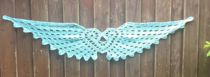 Mintgrüner gehäkelter Tischläufer mit offenem Wabenmuster und gezackter Kante, horizontal vor Holzbrettwand