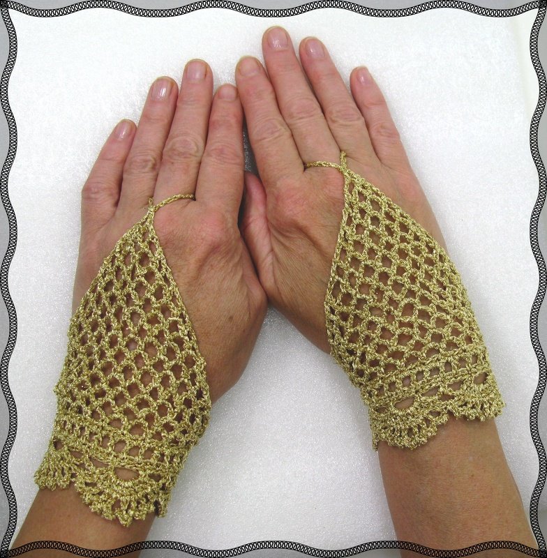 Goldene, gehäkelte fingerlose Handstulpen mit Spitzen- und Lochmuster, an beiden Händen getragen.