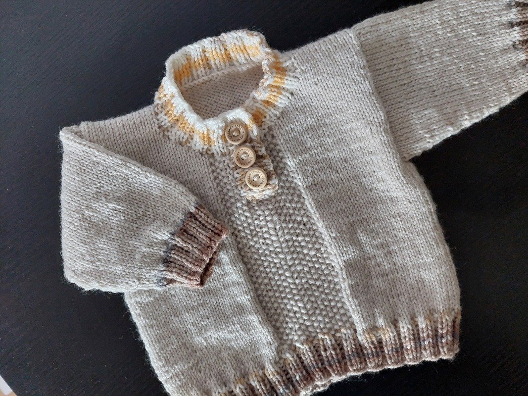 Beiger gestrickter Baby-Pullover mit drei Holzknöpfen und dezenten Streifen an Kragen und Bündchen