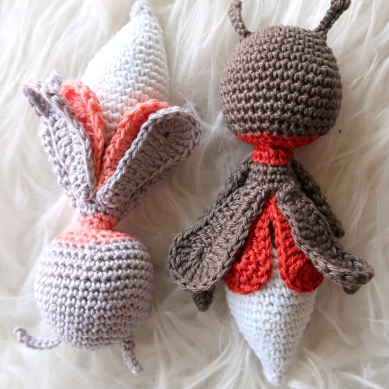 Zwei kompakte Amigurumi mit einfachen Körperformen, kontrastierendem Farbeinsatz und deutlicher Maschenstruktur auf hellem Hintergrund