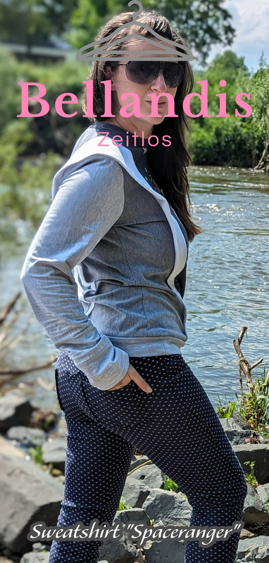 Seitenansicht einer Frau in grauem Kapuzen-Sweatshirt und dunkelblauer, gepunkteter Hose am Wasser.