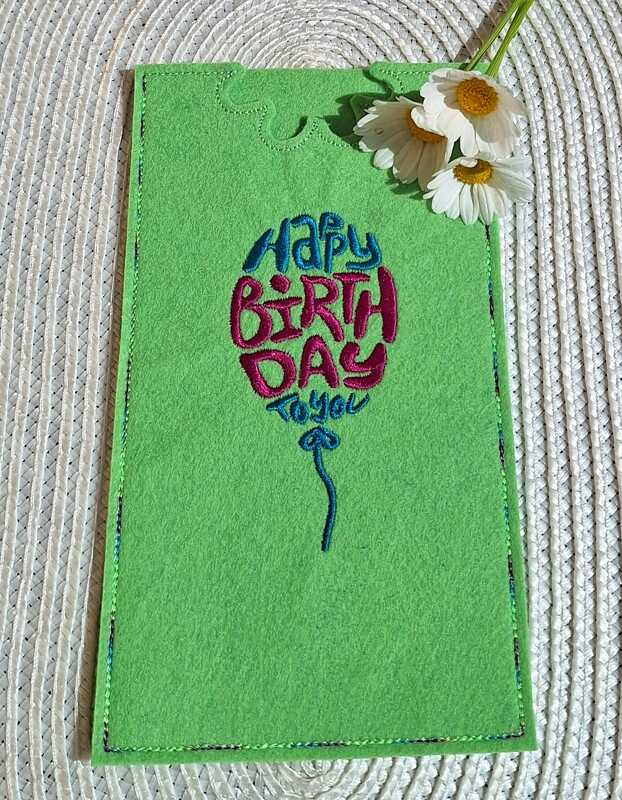 Grüner Filz mit besticktem 'Happy Birthday to you' Ballonmotiv, dekoriert mit Gänseblümchen.