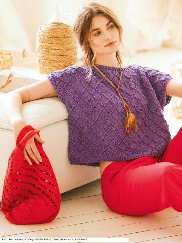 Violetter Pulli mit Noppenmuster und rote gehäkelter Tasche