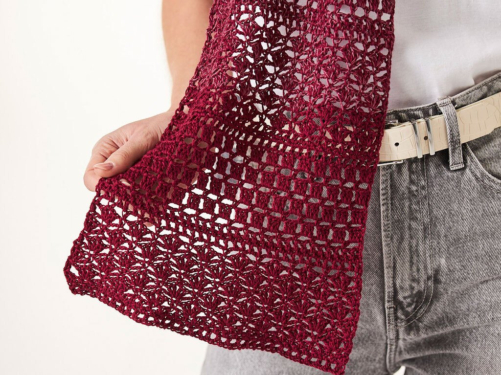 Bordeauxrotes gehäkeltes Rechtecktuch mit durchbrochenem Muster, Detailaufnahme, an der Taille gehalten