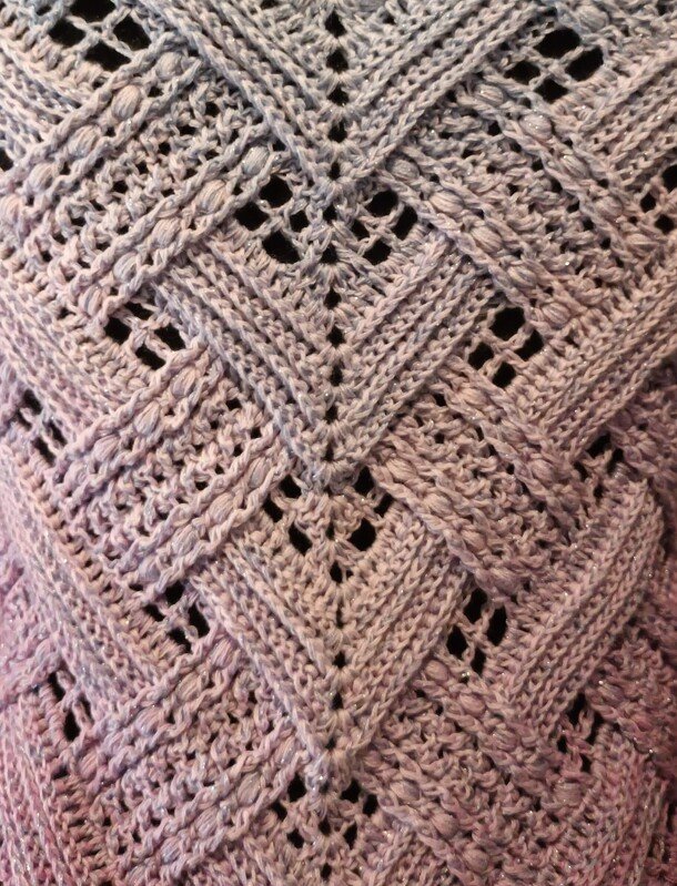 Close-up of a textured chevron triangle shawl in light lavender with bobble clusters and openwork.