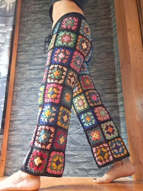 Full-length women's crochet pants made of colorful granny squares with dark joining and drawstring waist
