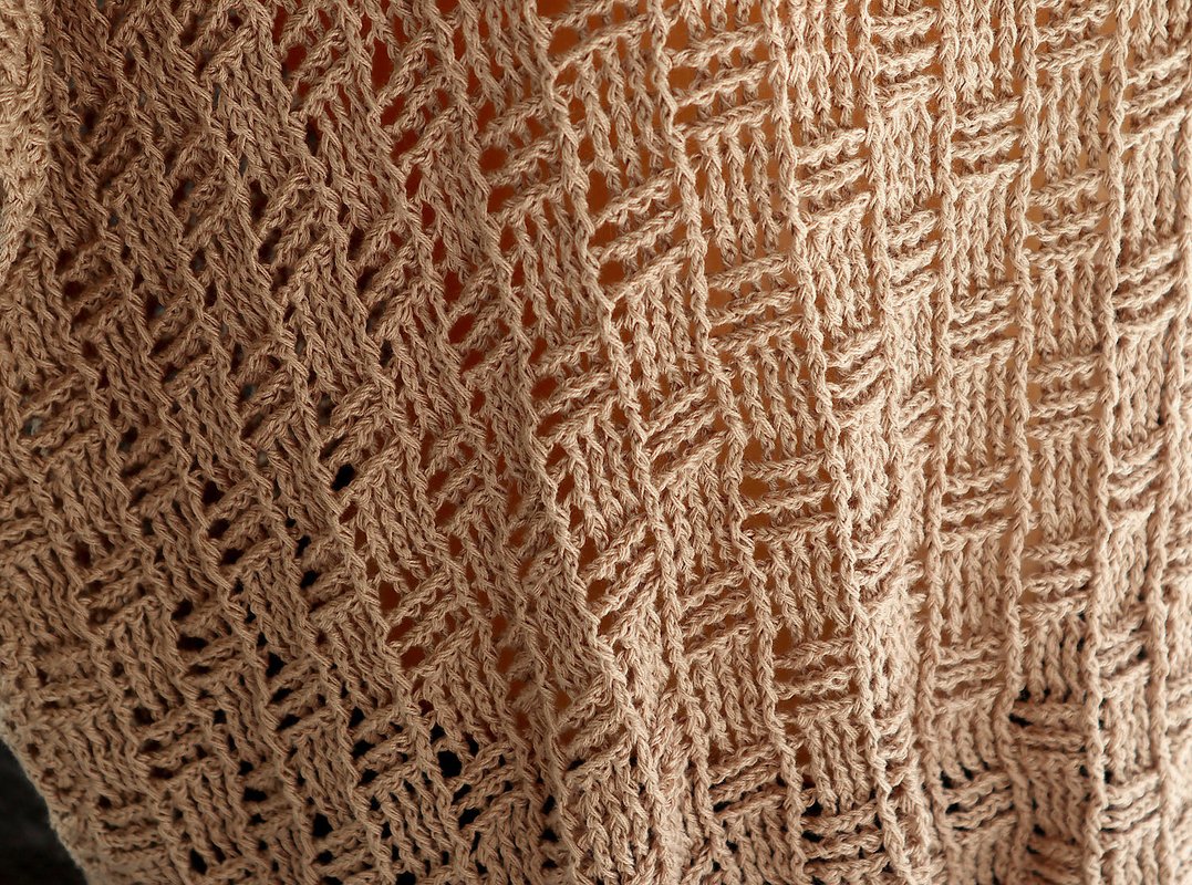 Beige crochet material displaying a consistent diagonal open-stitch pattern.