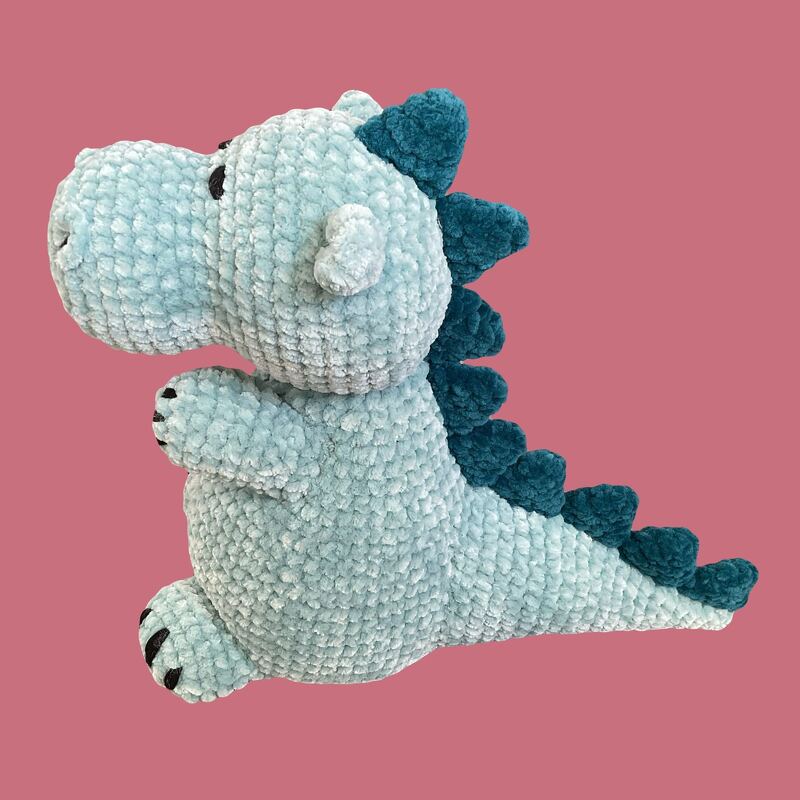 Seitliche Ansicht eines gehäkelten mintfarbenen Amigurumi-Dinos mit dunkeltürkisen Stacheln