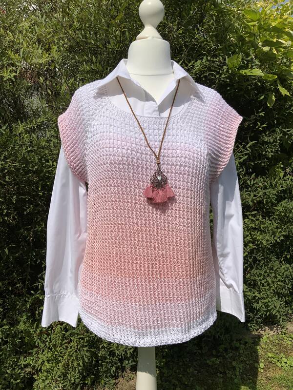 Gehäkeltes Weiß‑Rosa Ombre-Top mit Raglanschnitt auf Schneiderpuppe über weißem Hemd vor grünem Hintergrund