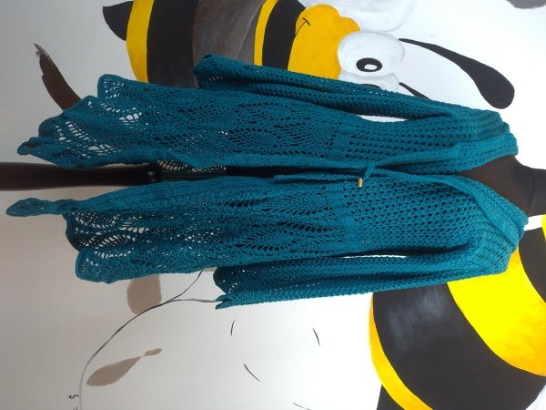 Petrolfarbene gehäkelte Damenjacke mit offenem Muster und Kordelzug.