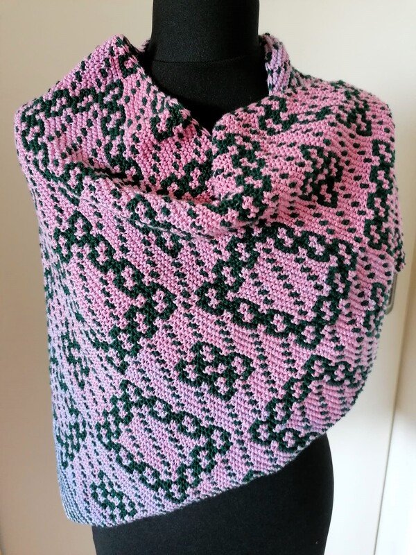Gestricktes Dreieckstuch in Rosa mit dunkelgrünen geometrischen Mustern, lässig auf einer Schneiderpuppe drapiert