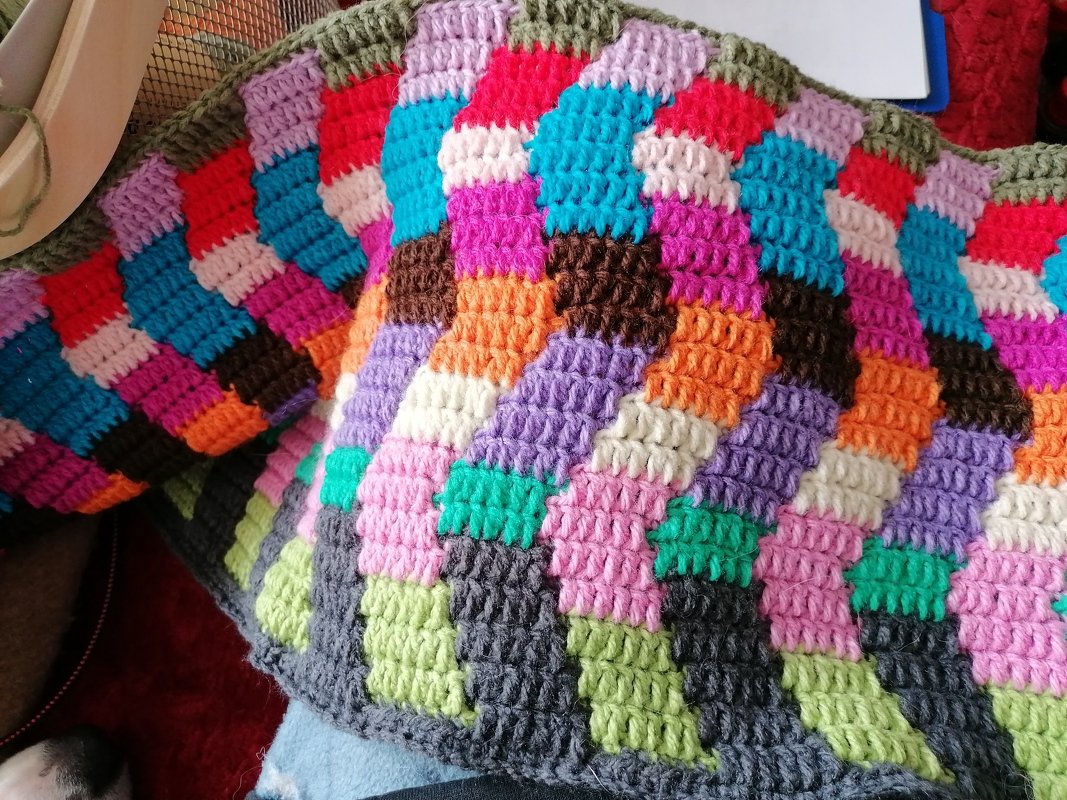 Nahaufnahme einer bunten gehäkelten Decke mit farbigen Quadraten