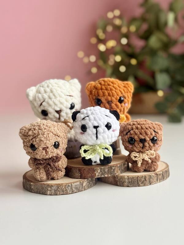Five small crocheted amigurumi teddy bears in different colors on wooden slices with a soft pink bokeh background