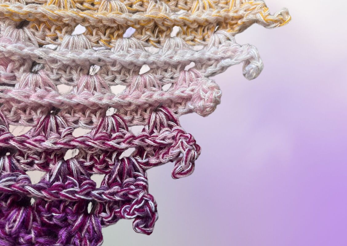Detailaufnahme gehäkeltes Dreieckstuch, Farbverlauf Gelb
RosaViolett mit Muschel- bzw. Fächerstichen und schimmerndem Garn.