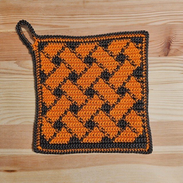Quadratischer gehäkelter Topflappen orange und dunkelgrau mit Flechtmuster und Aufhängeschlaufe