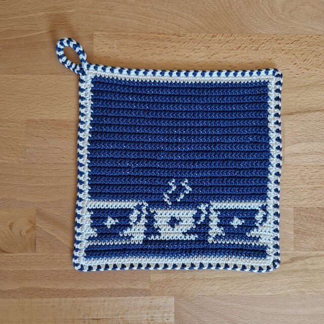 Quadratischer gehäkelter Topflappen blau-weiß mit Schlaufe auf Holzuntergrund