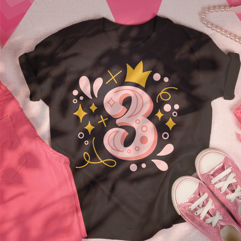 Schwarzes T‑Shirt mit großem rosa-goldenem Zahl-3-Design, Krone, Sternchen und Dekoelementen; daneben rosa Hose und glitzernde rosa Sneaker