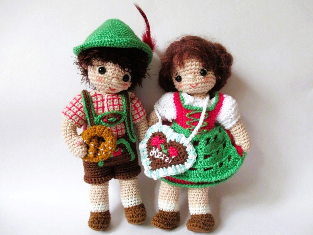 Zwei gehäkelte Amigurumi-Puppen in Tracht: Junge mit Lederhose und Brezel, Mädchen im Dirndl mit Lebkuchenherz