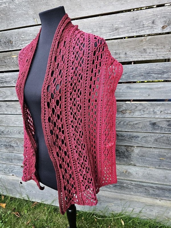 Bordeauxroter gehäkelter Spitzenschal mit Lochmuster auf schwarzer Büste vor Holzlatten