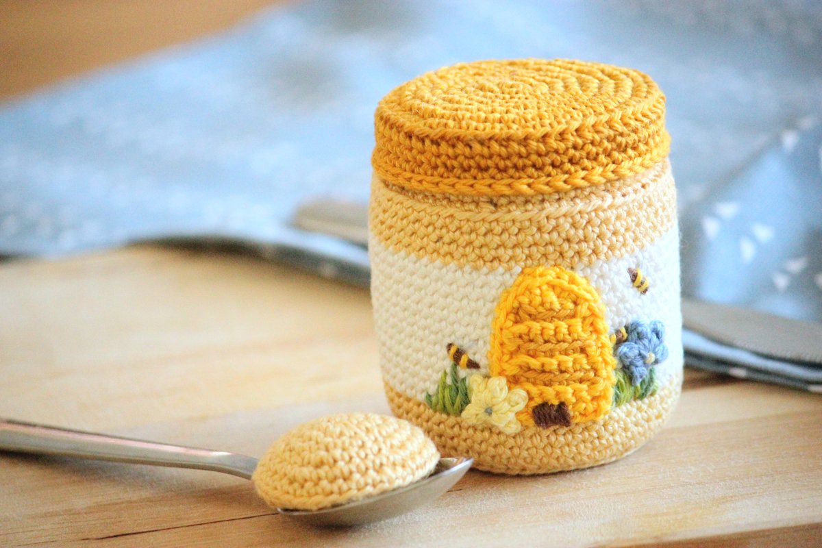 Gehäkeltes Honigglas in Gelb- und Cremefarben mit Bienenapplikation und Löffel