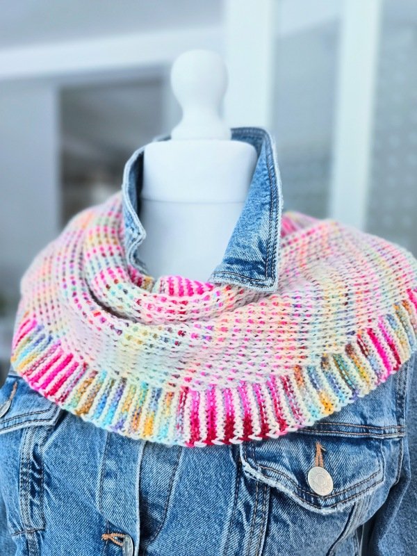 Gestricktes Dreieckstuch in Pastellfarben mit gerippter Kante über einer Jeansjacke auf einer Schaufensterpuppe