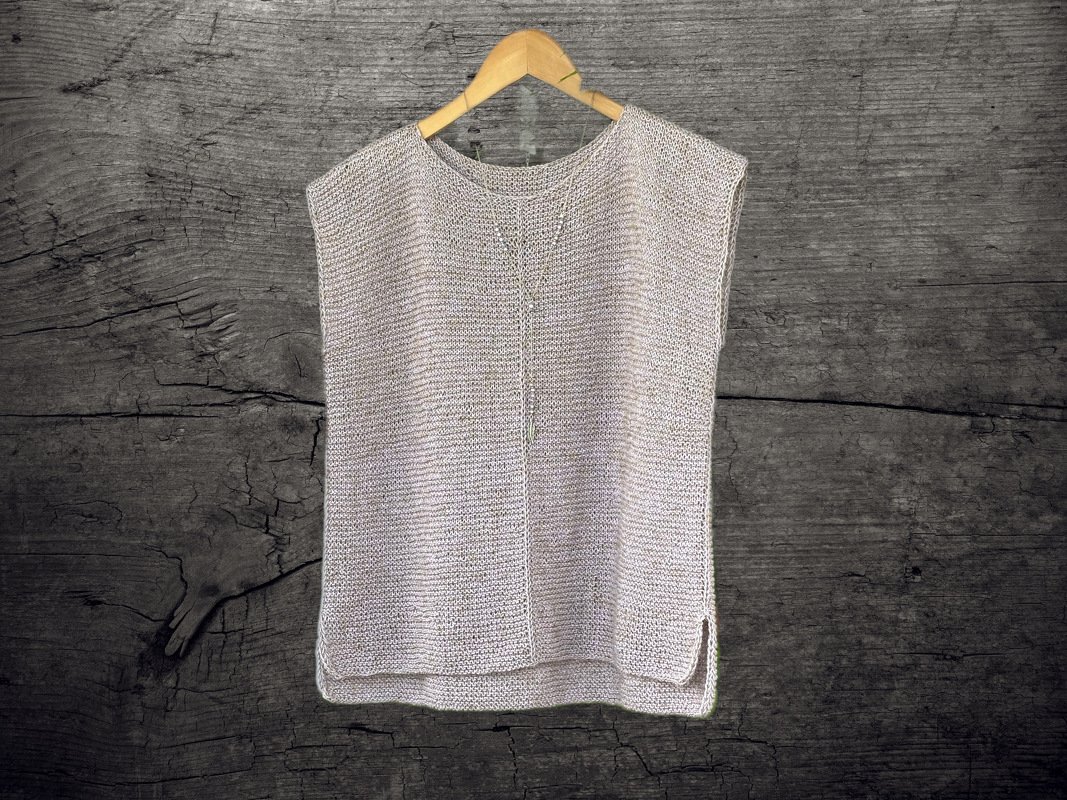 Neutral sleeveless knitted top with central V-stitch and side slits on a wooden hanger