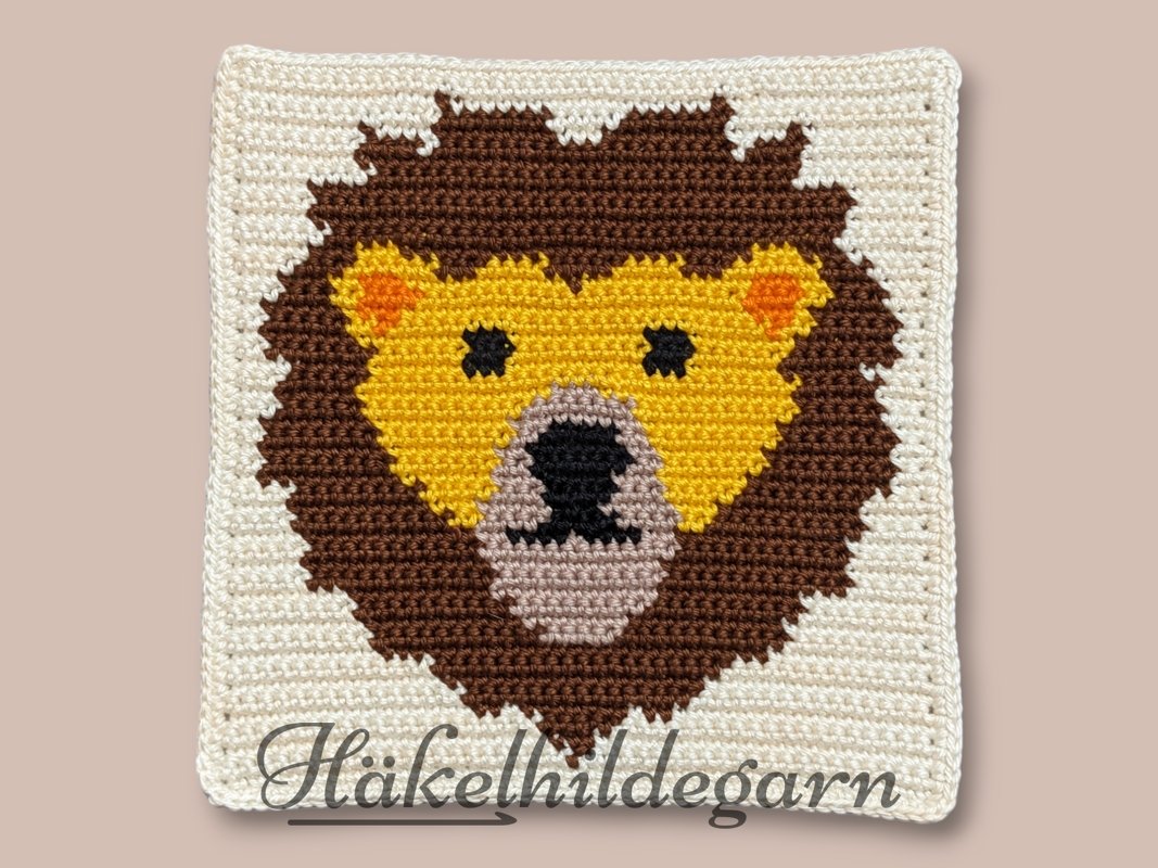 Quadratisches Häkelmuster mit pixelhaftem Löwenkopf und klaren Farbflächen