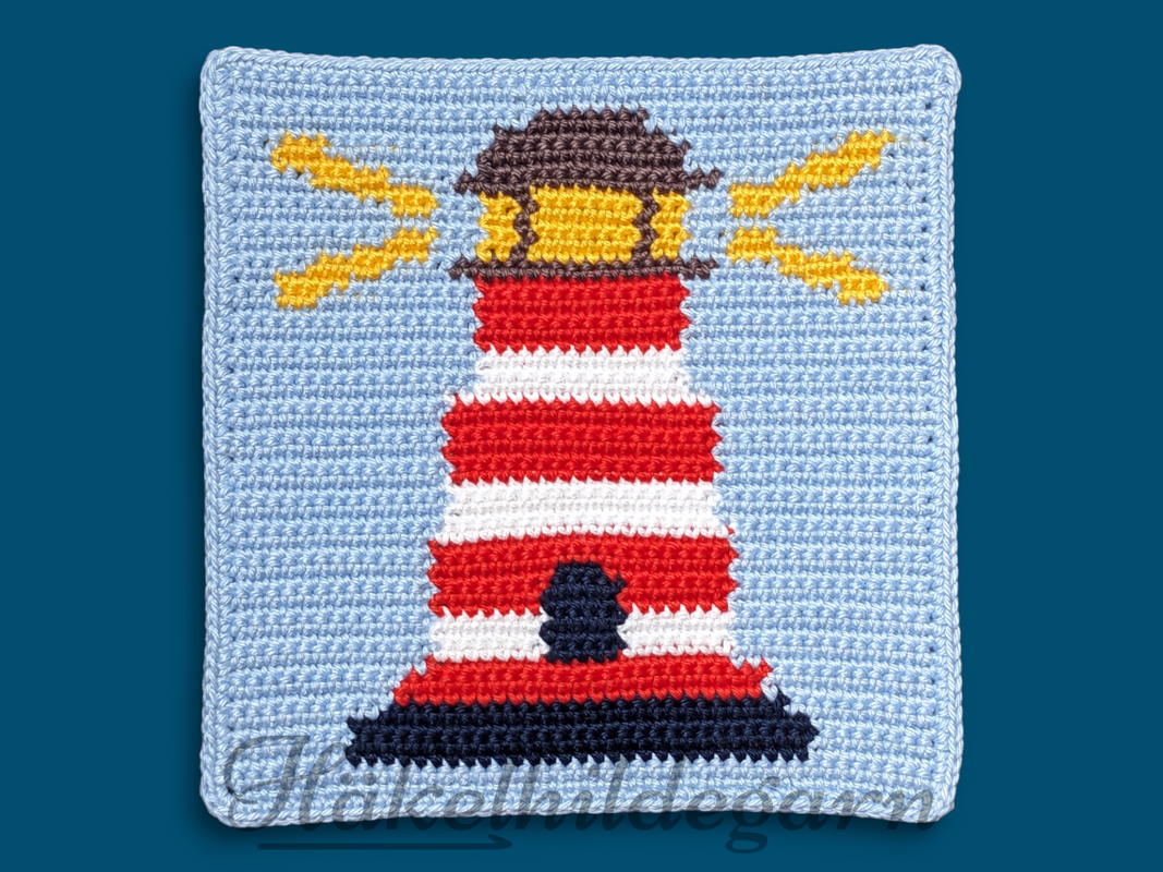 Gehäkeltes Quadrat mit rot-weiß gestreiftem Leuchtturm, dunklem Sockel und gelben Lichtstrahlen auf hellblauem Grund