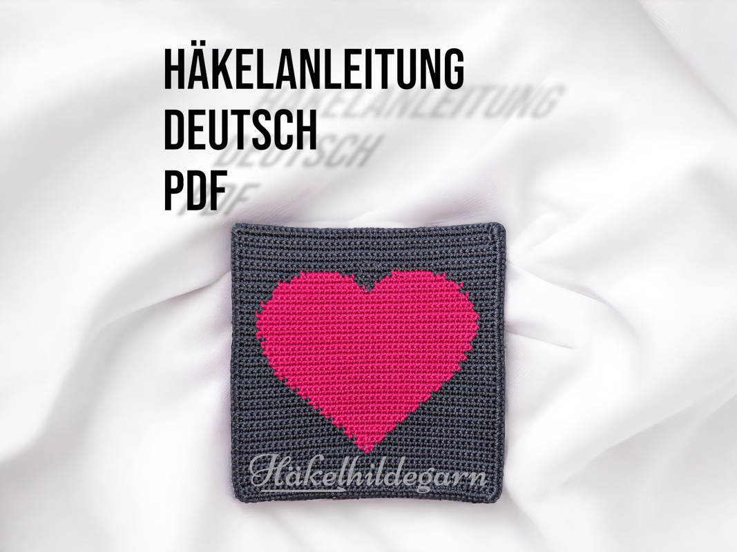 Quadratisches Häkelstück in Grau mit pinkem Pixel-Herz auf hellem Hintergrund