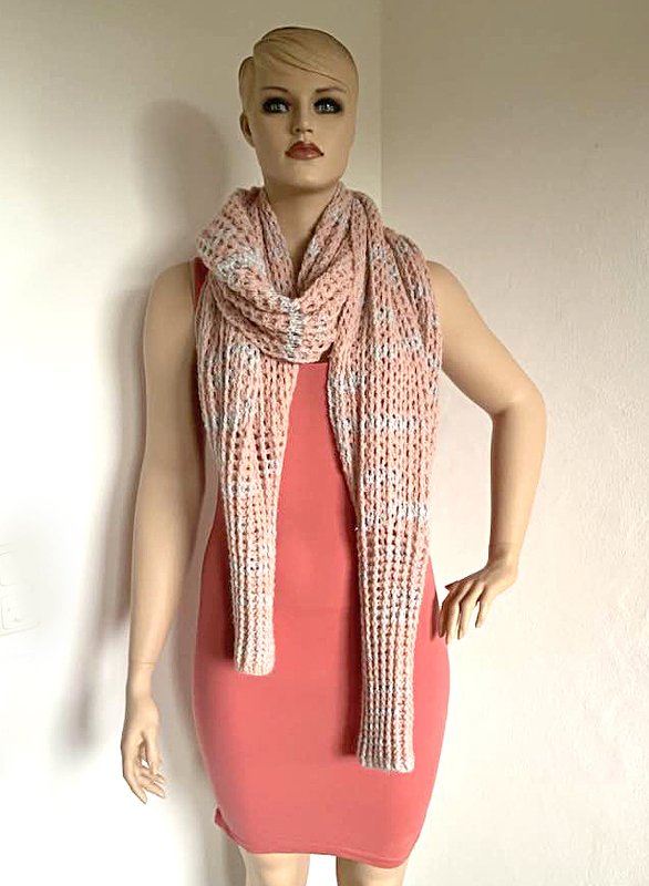 Gehäkelter rosé-weißer Schal an einer Schaufensterpuppe über einem korallfarbenen Kleid