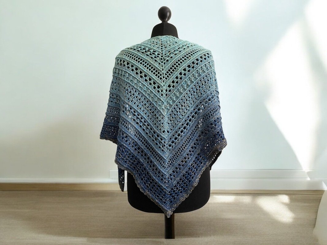 Blue-green ombre crochet triangle shawl draped on a black mannequin