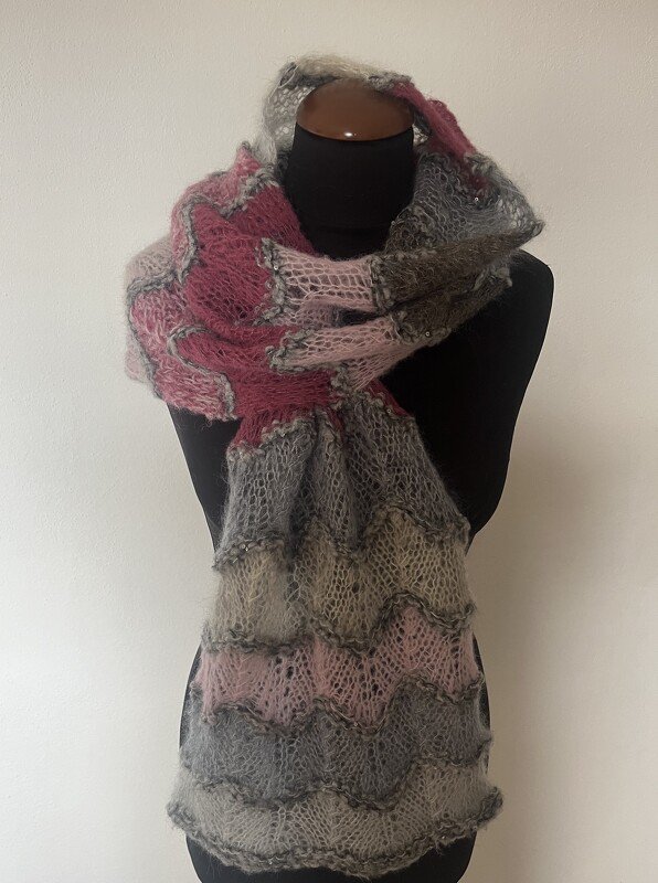 Gestrickter Schal in Grau und Rosa mit Wellenmuster auf einer schwarzen Schaufensterpuppe