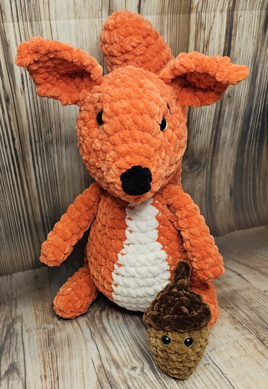Oranges, gehäkeltes Eichhörnchen-Amigurumi mit weißer Bauchpartie und kleiner gehäkelter Eichel