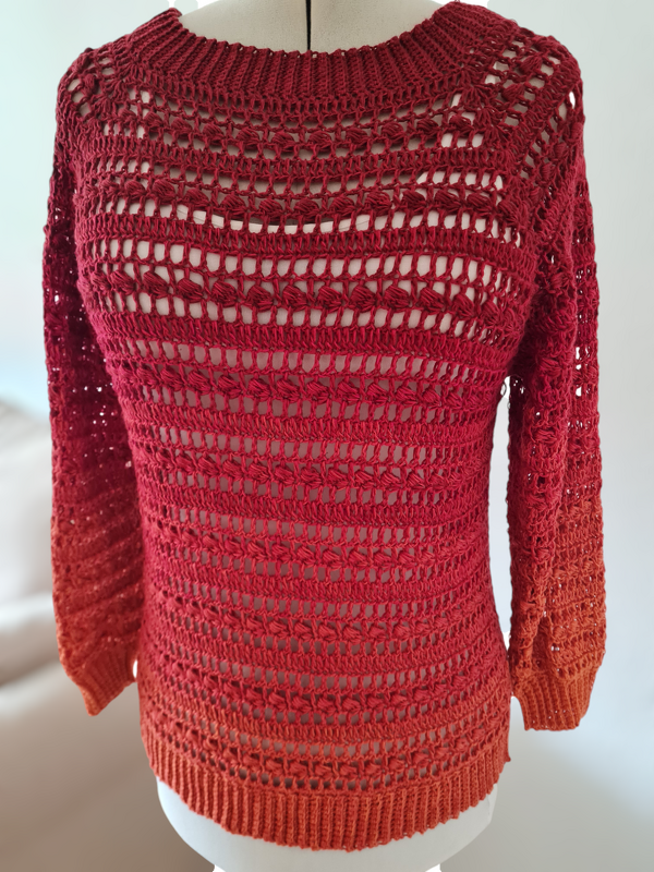 Rot‑Orange gehäkelter Damenpullover mit Ajourmuster auf Schneiderpuppe