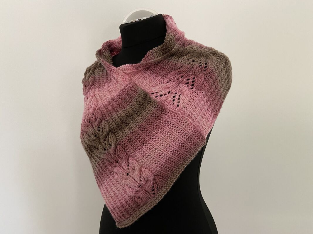 Dreieckiger gestrickter Kragenschal in Rosa- und Brauntönen mit Zopf- und Lochmuster auf schwarzer Schneiderpuppe